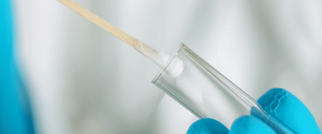 Gloved hand inserting swab into test tube